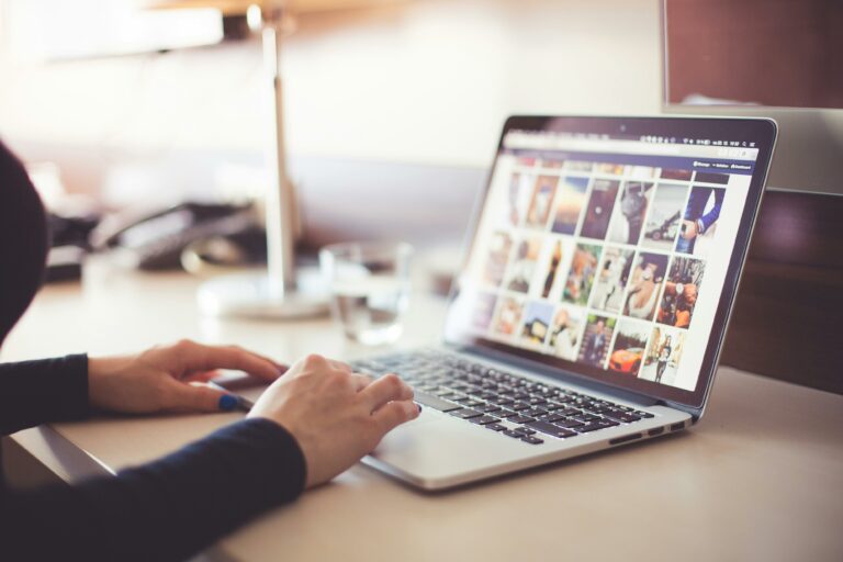 woman sitting at a desk with a MacBook pro laptop searching through images